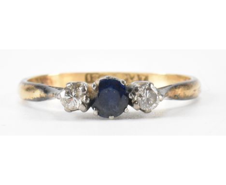 An 18ct gold sapphire and diamond three stone ring. The ring being set with a round cut blue sapphire flanked by two round cu