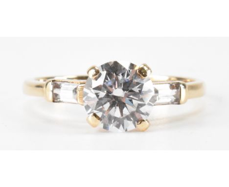A gold and white stone dress ring. The ring being set with a round brilliant cut cz with accent stones to the shoulders. Shan