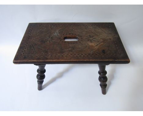 A late 18th/early 19th century fruitwood stool on turned legs, the top chip carved in the Jacobean style with rosettes, pomeg