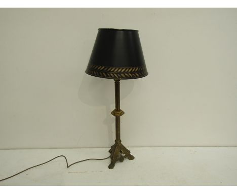 A tall brass and gilt metal table lamp with tri-form base on lion's paw feet and with a tole peinte lampshade.  