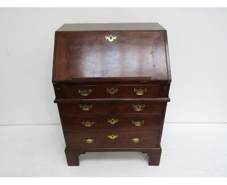 A small George II elm bureau the hinged fall revealing pigeon holes and drawers above one long, two short and two long drawer