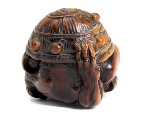NETSUKE.Japan, 2. Hälfte 19. Jh. H 3 cm.Buchsbaumholz, geschnitzt als Oni unter einem Strohhut als Schutz gegen Bohnenbewurf.