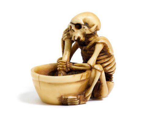 NETSUKE.Japan, 1. Hälfte 20. Jh. H 3 cm.Elfenbein, geschnitzt in Form eines Skeletts mit einem Mörser in der Hand und einem g