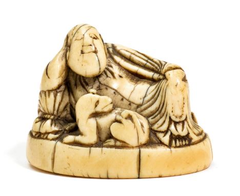 NETSUKE.Japan, ca. 1800, B 5 cm.Elfenbein. Ein liegender Europäer mit seinem Hund, auf ovaler Basis. Schöne Gebrauchspatina, 