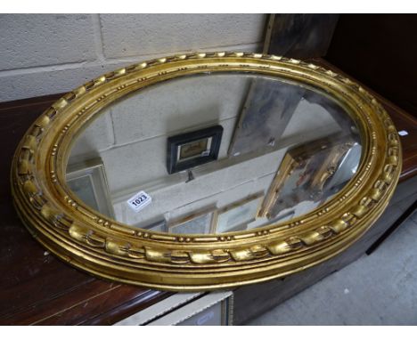 A mid-20th Century oval mirror with a gilt surround