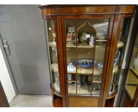 An Edwardian bow front mahogany display cabinet, with glazed front and side panel, inlaid with shell and flower boarder