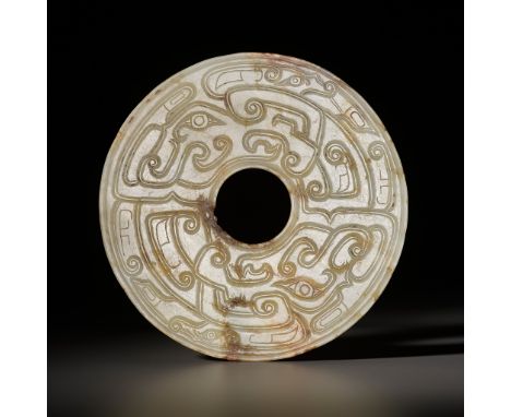 A JADE 'DRAGON' BI DISK, WESTERN ZHOU DYNASTYChina, 10th-9th century BC. The jade disk is carved on both sides with profiles 