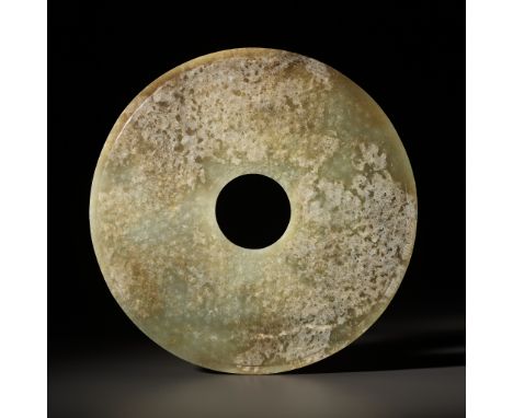 A CELADON AND BROWN JADE BI DISK, WESTERN HAN DYNASTYChina, 2nd-1st century BC. Each side finely carved in low relief with a 