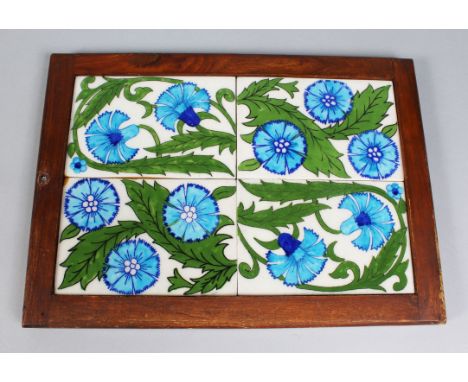 A FRAMED SET OF FOUR WILLIAM DE MORGAN TILES, painted in polychrome and decorated with blue flowers amongst leaves. Frame 14i