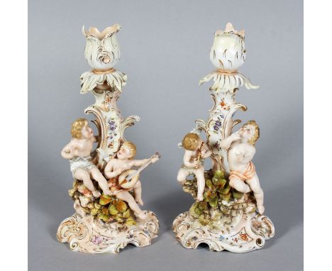 A PAIR OF CONTINENTAL PORCELAIN CANDLESTICK GROUPS with two cupids. 7.5ins high.