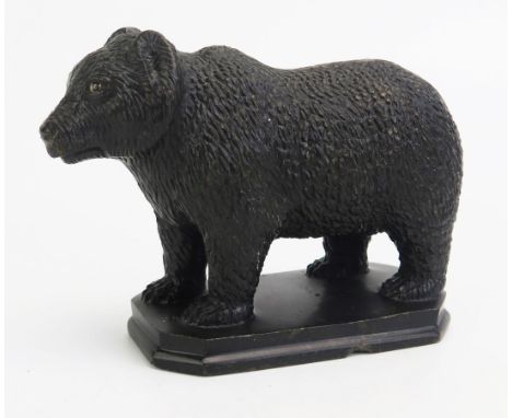 A carved hardstone model of a bear, in the Black Forest style, with inset glass eyes, on a rectangular plinth base, 15cm long