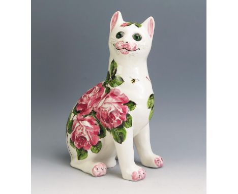 An Exon Ware Wemyss pottery cat: modelled seated with turned head curled tail and with inset green glass eyes, painted with p