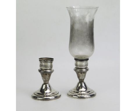 A pair of sterling silver storm lamp bases, with pierced sconces, on a domed weighted base, one with glass chimney. 
