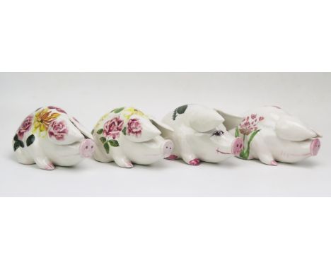 A group of four Exon Wemyss style pottery pigs, with painted floral decoration, one impressed PA, another signed P.A. (4) 