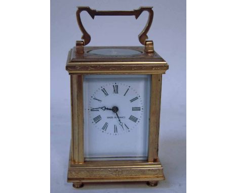 A small French brass carriage clock, 20th century, white face with Roman numerals, foliate chased case with five glass panels