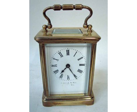 A late 19th/early 20th century brass carriage clock with gilt brass five panel case, white face with Roman numerals, inscribe