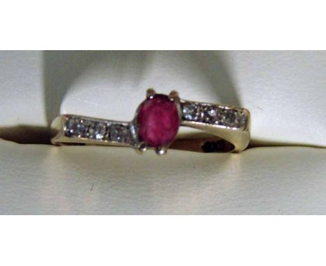 A modern 9ct gold ruby and diamond dress ring of cross over style, the central ruby flanked by two shoulders of three small d