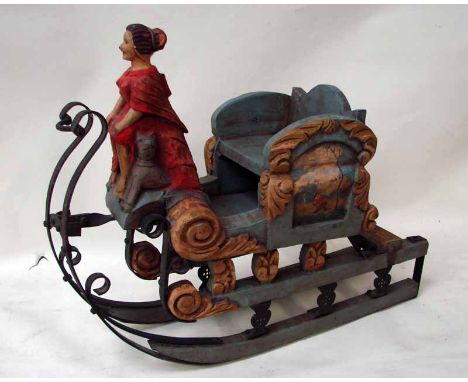 A carved painted wood an wrought iron Troika style model sleigh, seated woman up front in a cloak with two dogs, 53cm long 