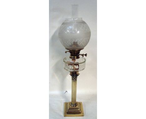 A Victorian brass oil lamp etched glass globe shade, clear glass drum shape reservoir with twin wick burner, set on a Corinth