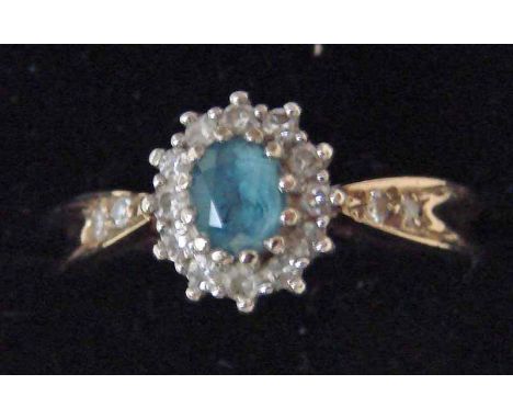 A modern 9ct aquamarine and diamond cluster ring of oval form with a central aquamarine surrounded by small diamonds, size K