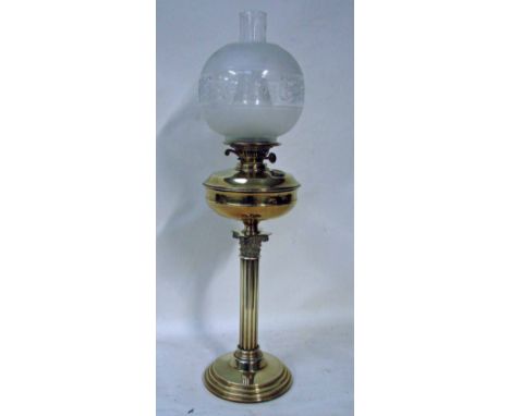 A Victorian brass oil lamp, etched glass globe shade, brass reservoir with duplex burner, set on a Corinthian style column su