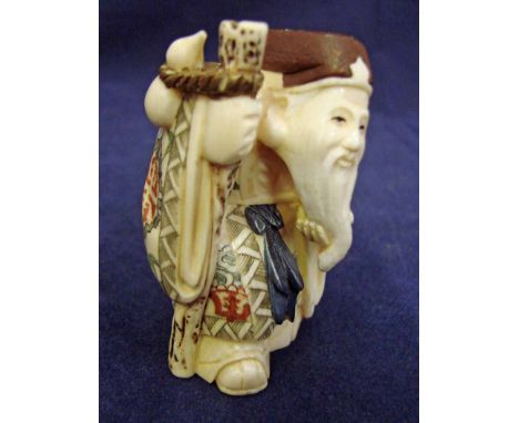 A Japanese carved ivory Okimono as a bearded elderly man holding a stick suspending a gourd, 6.5cm high 