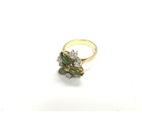 An 18ct gold art deco floral styled ring set with diamonds and green stones. Approx 7.23 grams, size N.