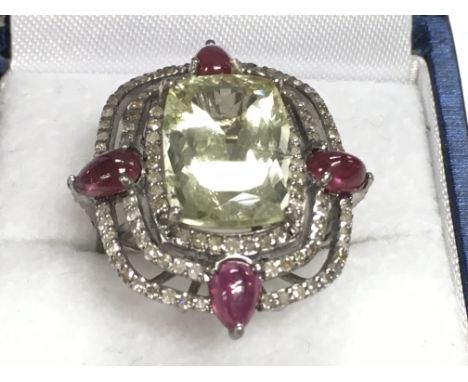 Large cluster dress ring in white metal set with central green beryl surrounded by pear shaped rubies and R/C diamonds, boxed