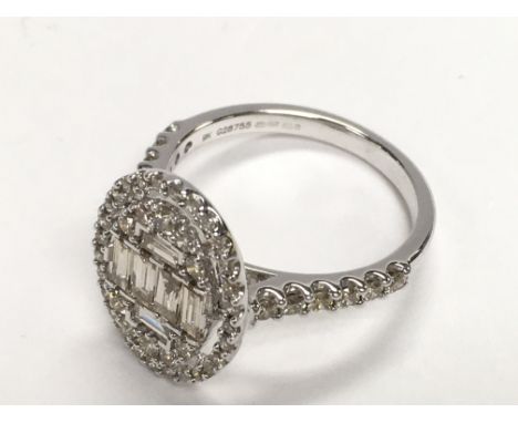 Large oval cluster ring set with baguette cut and round brilliant cut diamonds with diamond shoulders, set in 9ct white gold.