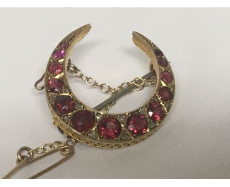 A 9carat gold crescent brooch set with a row of graduating ruby coloured stones weight 3g