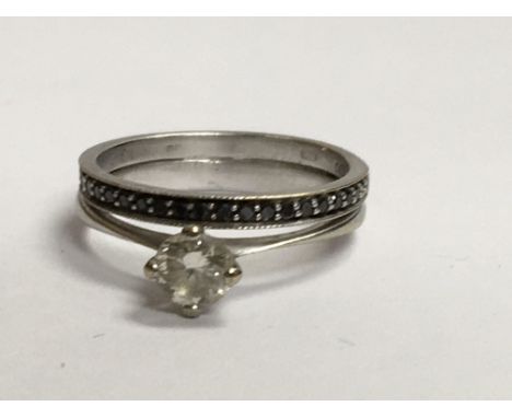 A 18 ct white gold ring with central diamond surround by black diamond chips . Size k .