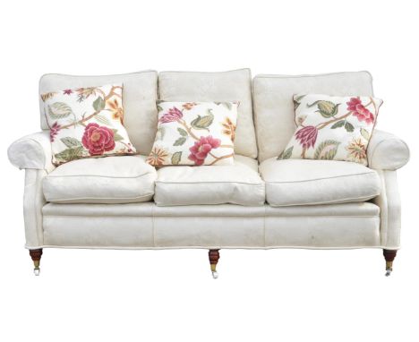 A Victorian style upholstered three seater sofa, covered in foliate figured cream fabric, with loose seat and back cushions ,