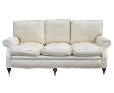 A Victorian style upholstered  three seater sofa, covered in foliate figured cream fabric, with loose seat and back cushions,