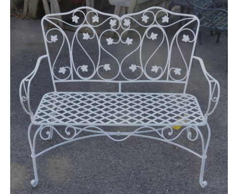 A white painted two seat garden sofa, with pierced foliate scrolling back, scrolling arms, on cabriole legs joined by a stret