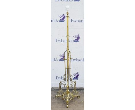 A late Victorian brass standard lamp, the central stem enclosed by openwork scroll arms, on a pierced domed base with triple 