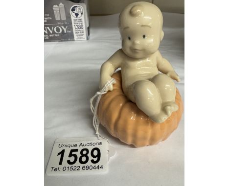 A NAO figure of a baby sat on a pumpkin.