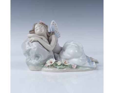 This Lladro figurine, titled Princess of the Fairies, depicts a delicate fairy peacefully resting on a stone surrounded by fl