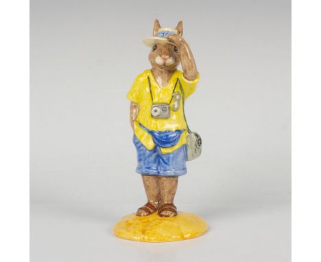 A bunny on vacation wearing a yellow top, blue shorts, fanny pack, with a camera hanging from his neck. RDICC. This item come