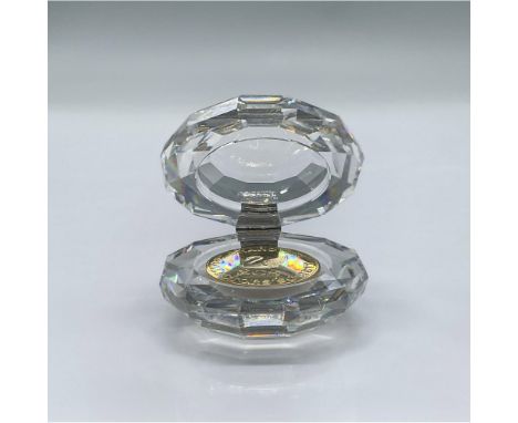 A faceted clear crystal round box with a golden hinge and golden coin. This item has its original box: 3.25"L x 3.25"W x 2.5"