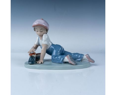 Lladro All Aboard figurine, model number 07619, features a young boy joyfully playing with a toy train. Sculpted by Jose Roig