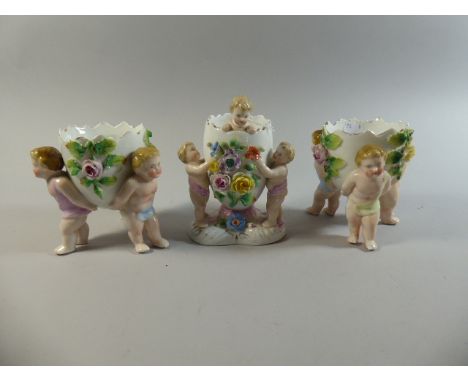 A Garniture of Ceramic Floral Encrusted Eggs with Cherub Supports 