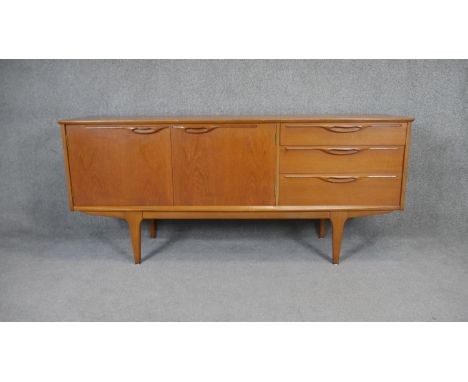 A 1970's vintage teak sideboard with cupboards and drawers on shaped tapering supports.  H.74 W.168 D.45cm 