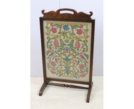 Arts and crafts mahogany fire screen with glass screen and hand carved pediment housing a wool work needlepoint tapestry pane