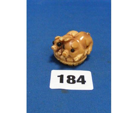 A Netsuke in the form of two pigs in a basket carved from a nut with two character mark to base.
