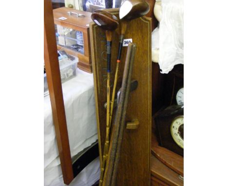A collection of vintage hickory handled golf clubs and woods and a vintage oak golf club display wall plaque.
