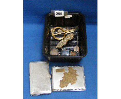 A box of cigarette lighters, a Jaws harp, silver coins and a silver arrow.    
