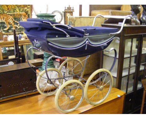 A Silver Cross carriage built dolls pram with matching bag, fitted chrome storage shelf below.