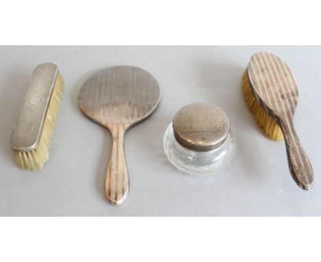 Four silver dressing-table requisites: a handheld mirror and matching hairbrush, engine turned and with gold-coloured striped