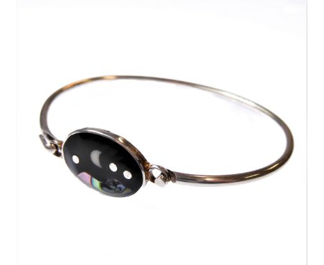 A silver bangle with hook style clasp: centrally set with a dark hardstone mounted with mother of pearl and a crescent-shaped