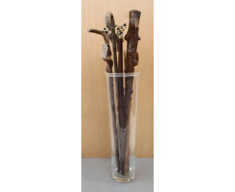 A modern glass stick or umbrella holder and nine walking sticks to include an early 20th century bamboo example with carved e